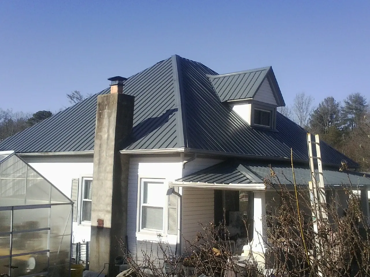 Dark blue standing seam metal roof on a white farmhouse with dormer — Slate & Tile Roof Repair by Roofing Brothers in Tooele