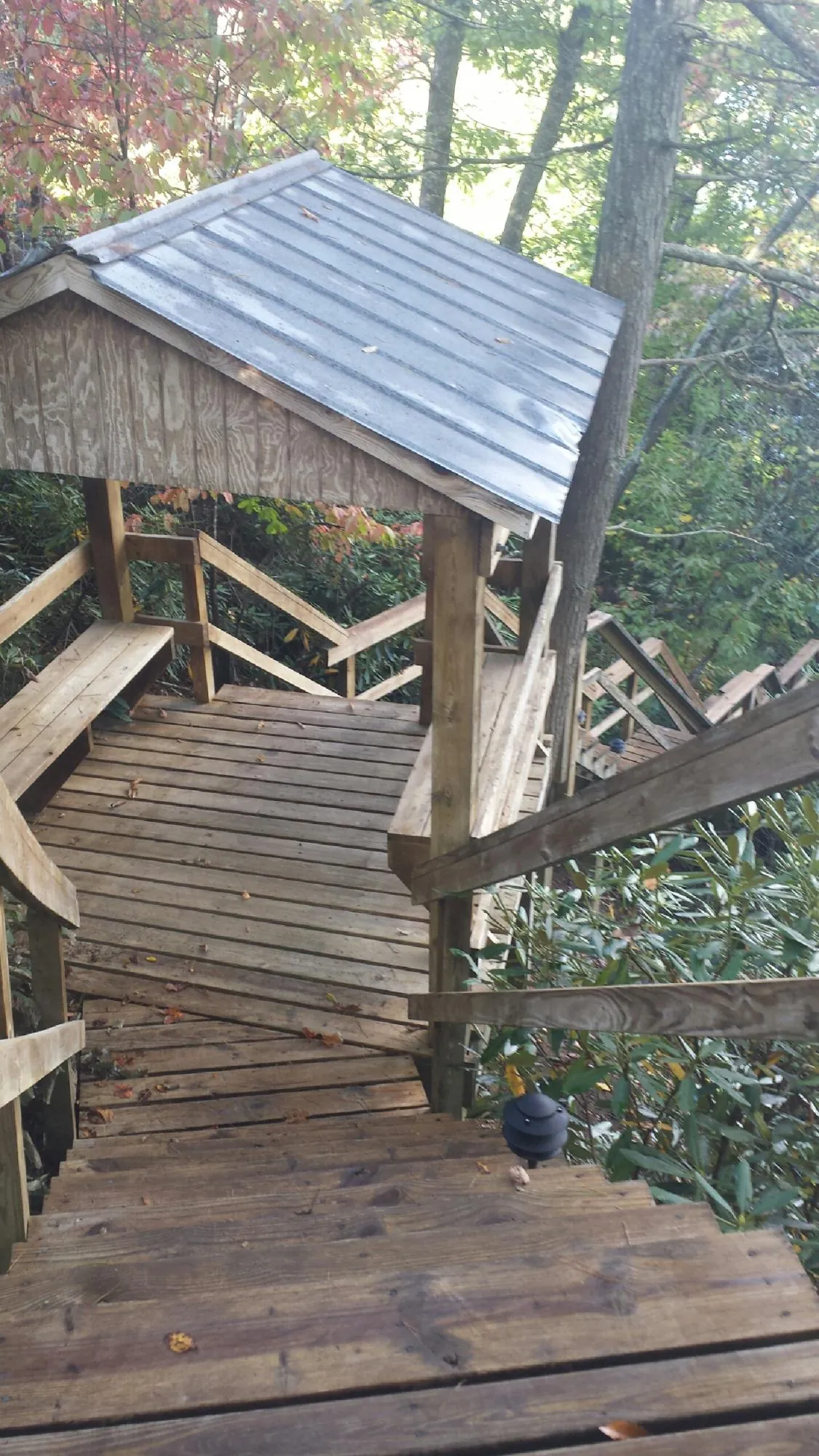 Metal roofed shelter over wooden steps on a wooded walkway — Skylight Repair & Installation work by our crew in Tooele