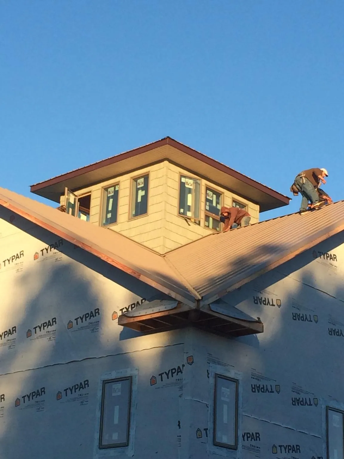 Roofers working around a rooftop cupola on a new metal roof at sunset — Roof Waterproofing in Tooele by Roofing Brothers